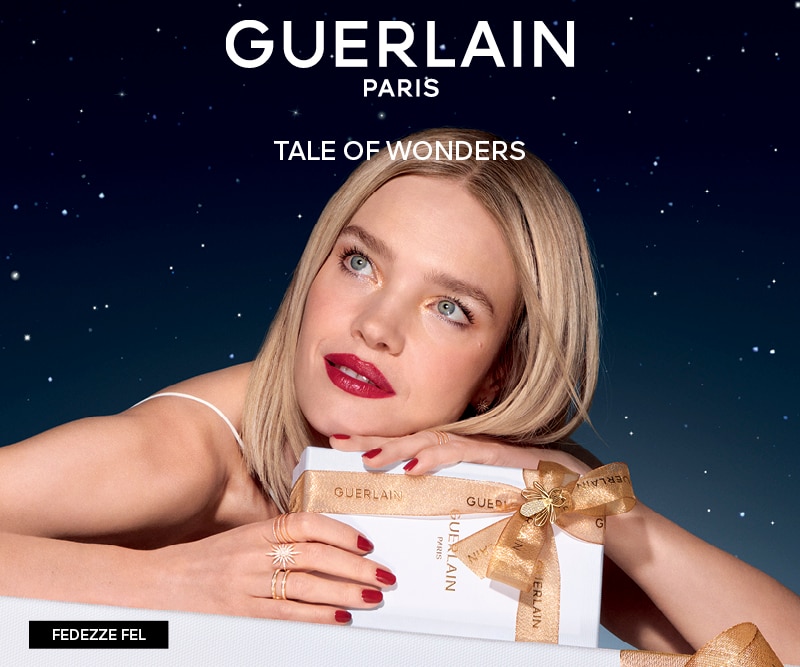 Guerlain ajándékdoboz arany masnival, luxus parfüm és szépségápolási termékek elegáns csillagos háttér előtt.